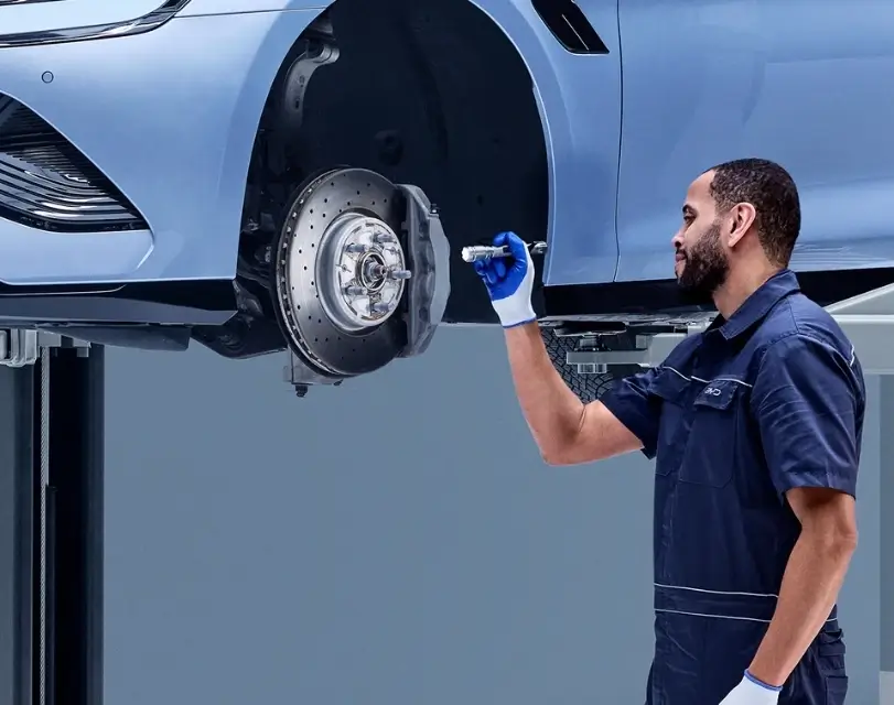 Mecânico BYD mexendo na roda de carro suspenso.